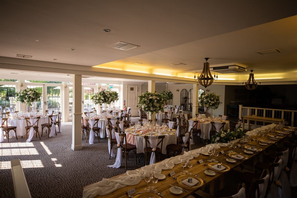 Stone Manor wedding room decorated with white chair covers, flowers on the tables and pink roses.
