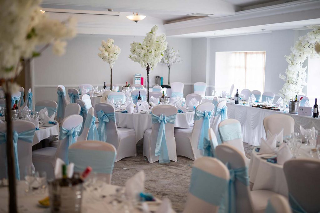 Photo of Aylesford Suite set up for a wedding reception with round tables and turquoise chair sashes